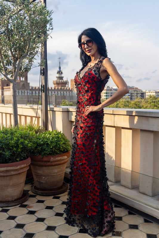 Daisy Noir by Preema Aura styled over a vibrant red satin slip, creating a bold contrast beneath the black floral appliqué on a luxury rooftop setting.