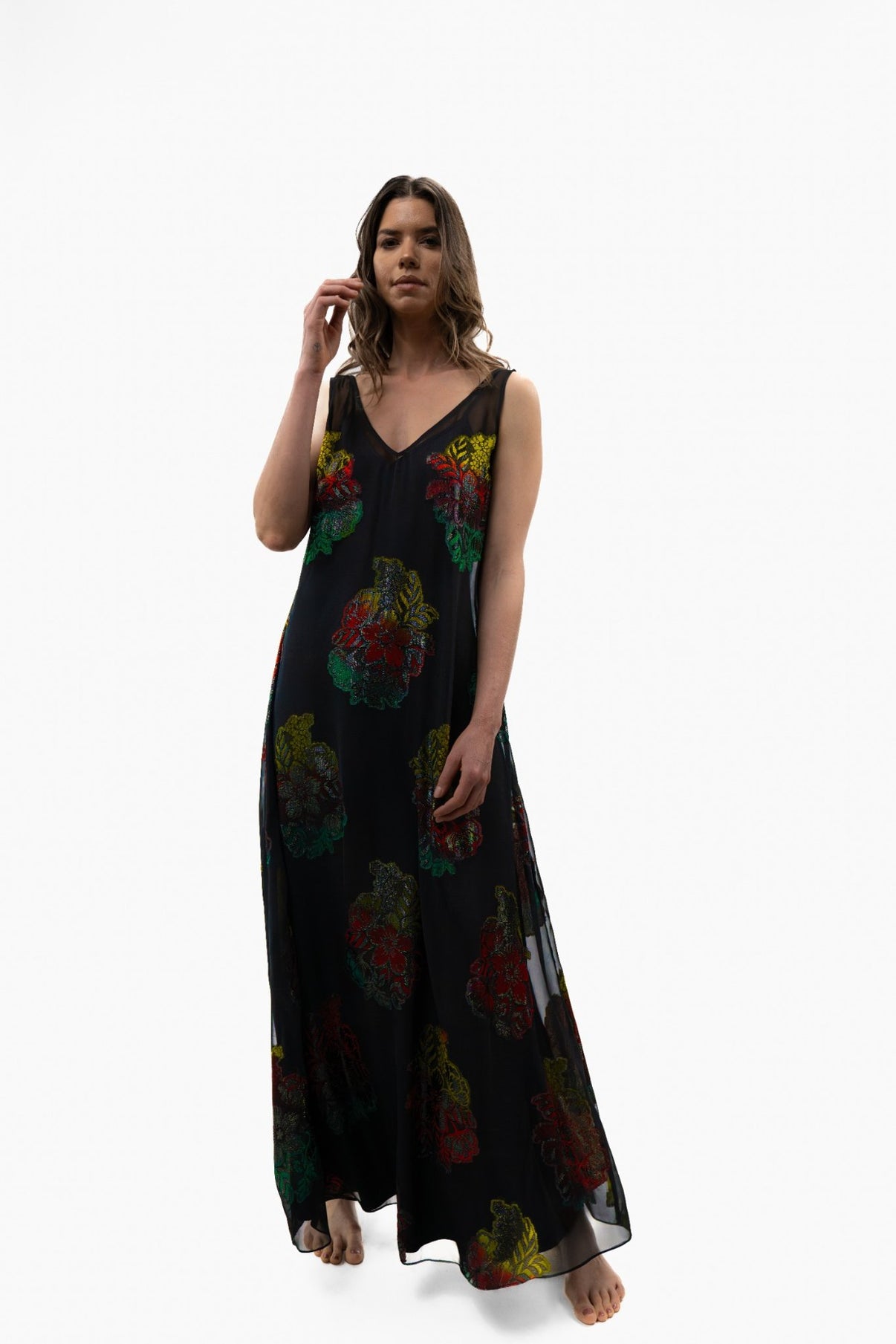 Model wearing the Preema Aura Soul Series Dusky Rose dress, a black French-silk gown with hand-finished red, green and yellow floral detailing, shown full length for its fluid drape and elegant silhouette.