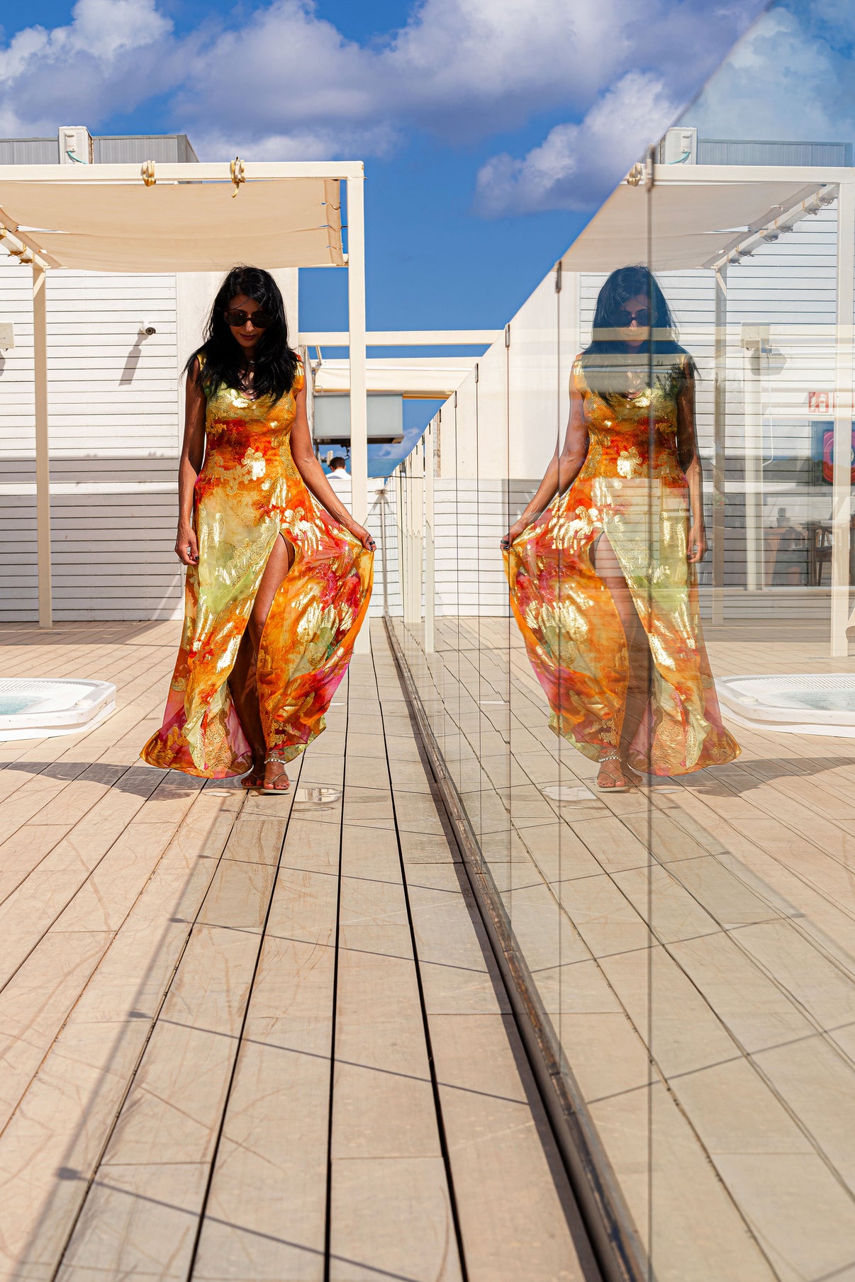 Woman wearing the Mystique Horizons dress by Preema Aura, showcasing a reflection of its gold, red, yellow and orange colours.