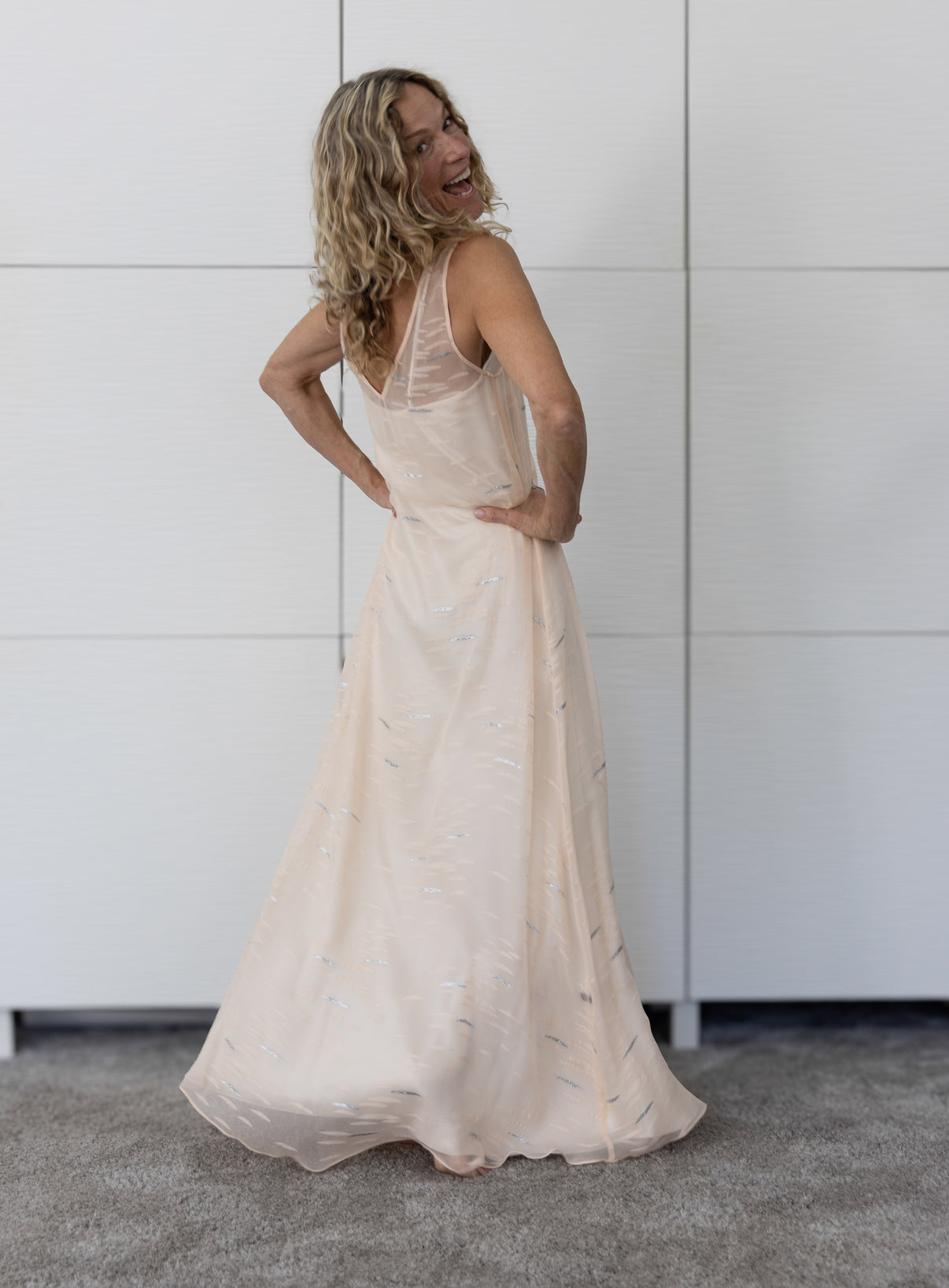 Soul Flare by Preema Aura – back view of sheer nude maxi dress over a cream slip, highlighting its delicate transparency and flowing silhouette.