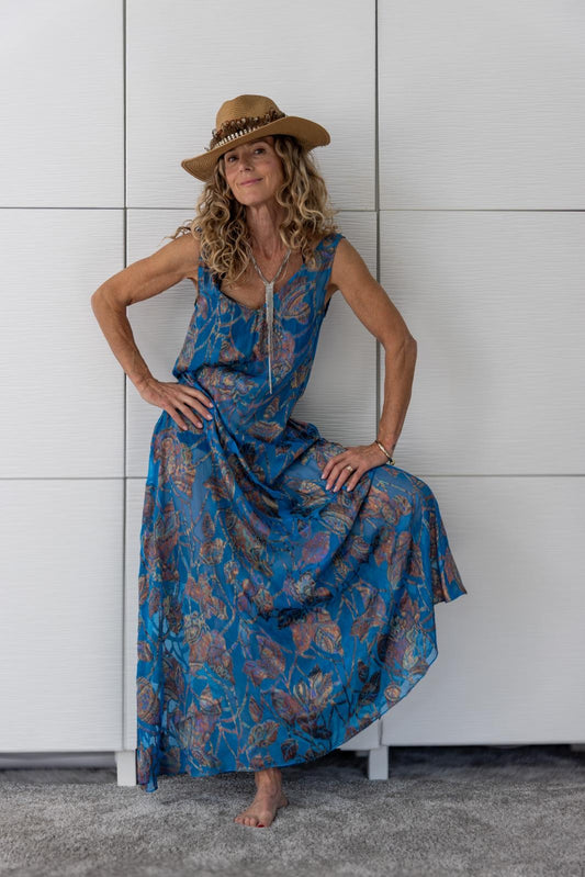 Woman wearing the Soul Drift dress by Preema Aura, a sheer blue maxi dress with soft metallic floral detailing from the limited-edition Soul Series, capturing its free-spirited resortwear aesthetic and graceful movement.