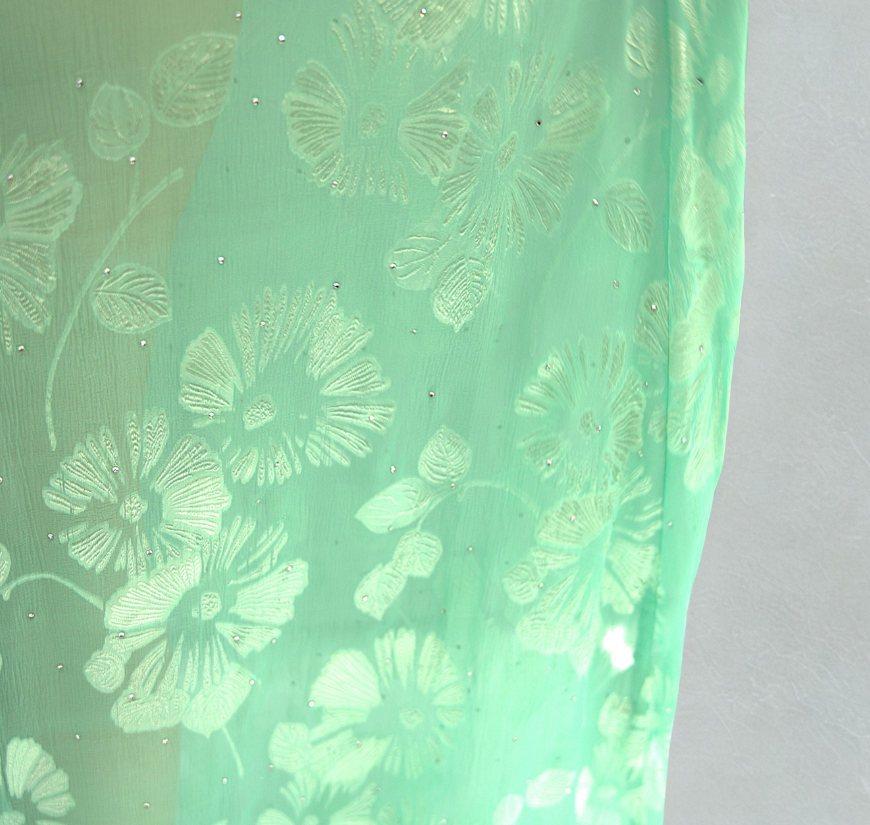Close-up of Soul Eden silk fabric showcasing delicate green floral embroidery and subtle crystal embellishments.