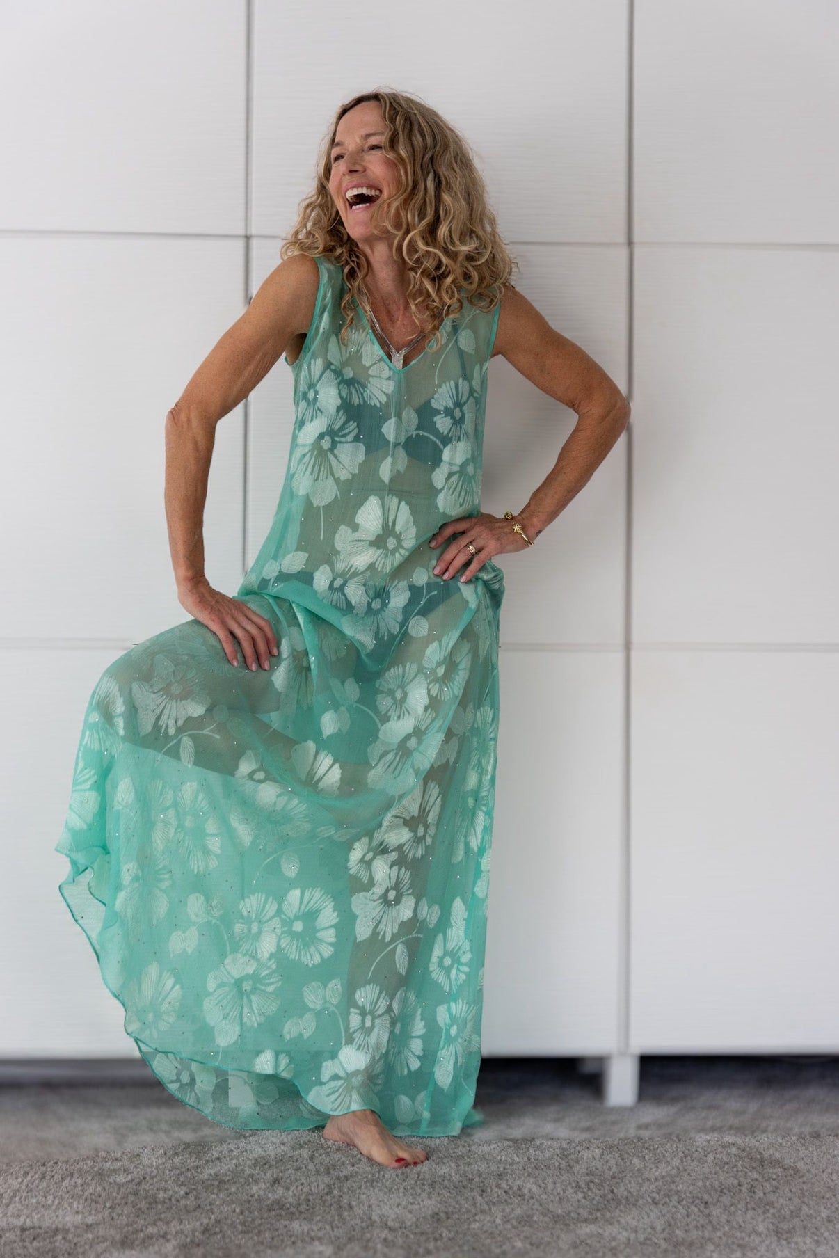Woman wearing the Soul Eden dress by Preema Aura, a translucent aqua-green maxi layered over a bikini, featuring white floral detailing and fluid movement from the limited-edition Soul Series collection.