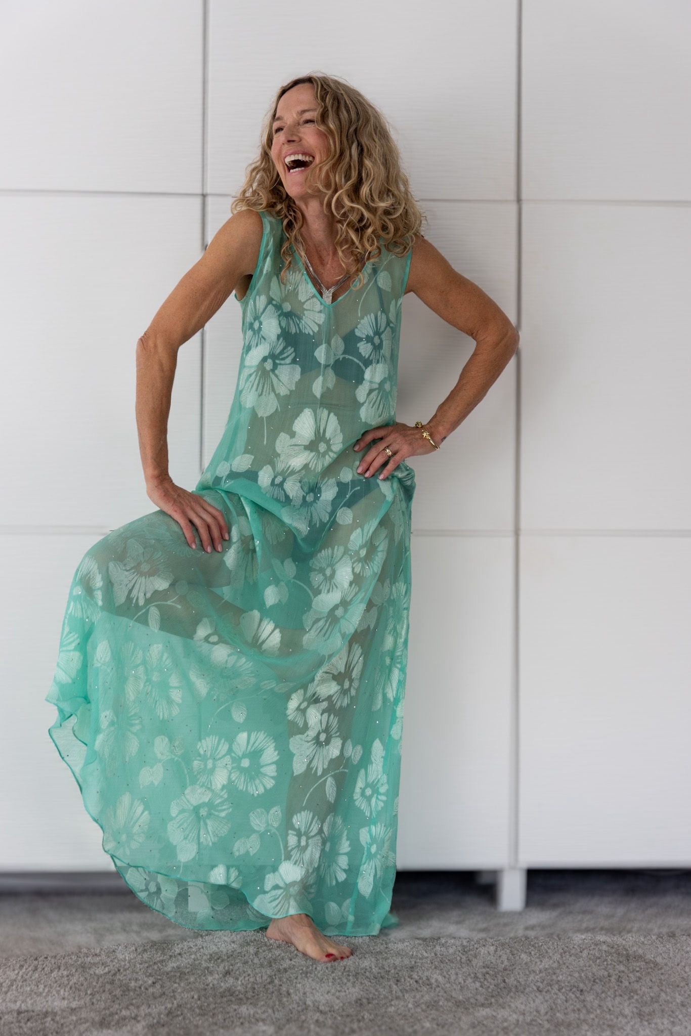 Woman wearing the Soul Eden dress by Preema Aura, a translucent aqua-green maxi layered over a bikini, featuring white floral detailing and fluid movement from the limited-edition Soul Series collection.
