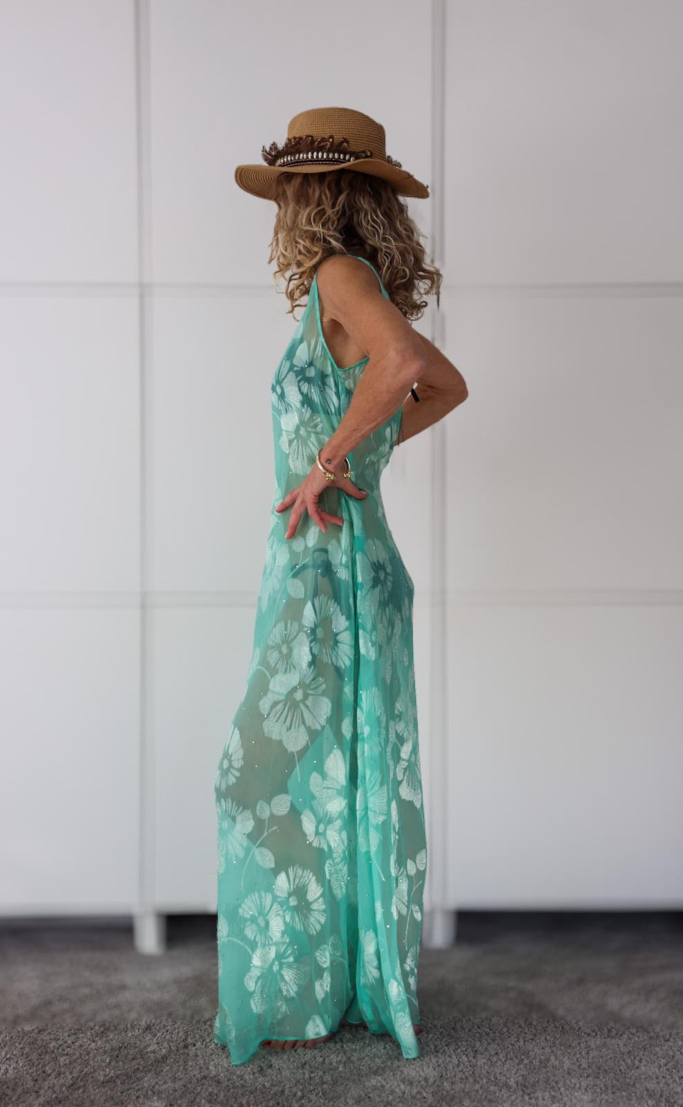 Side view of the Soul Eden dress by Preema Aura, showcasing its sheer turquoise fabric with soft white floral pattern and graceful silhouette, part of the exclusive Soul Series of one-of-a-kind resortwear designs.