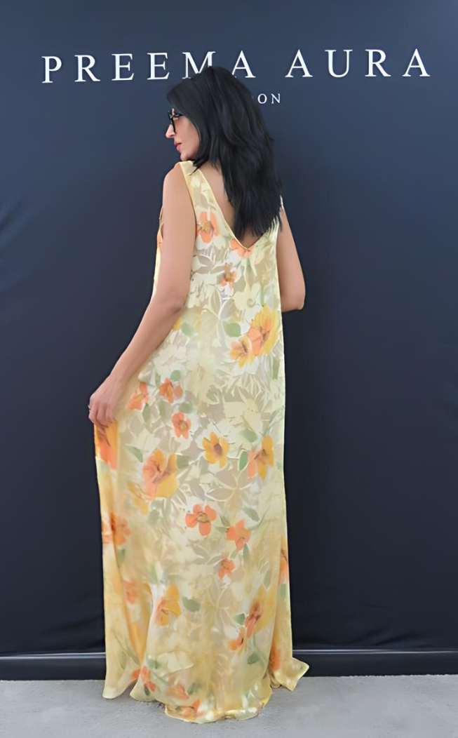 Back view of Preema Aura Soul Series Solstice dress – sheer silk maxi gown in soft gold tones with hand-painted floral print in warm orange and green hues