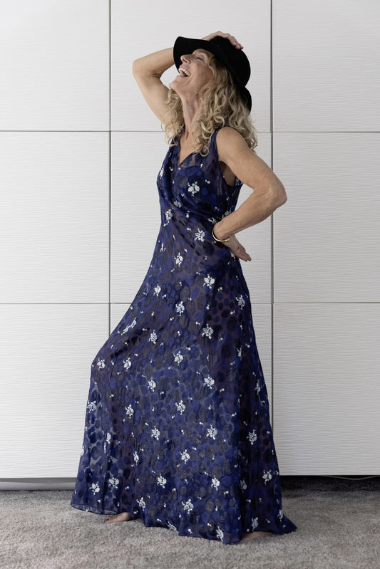 Woman laughing in elegant navy sheer Preema Aura Soul Nightfall dress with delicate floral detailing, luxury resortwear made in London