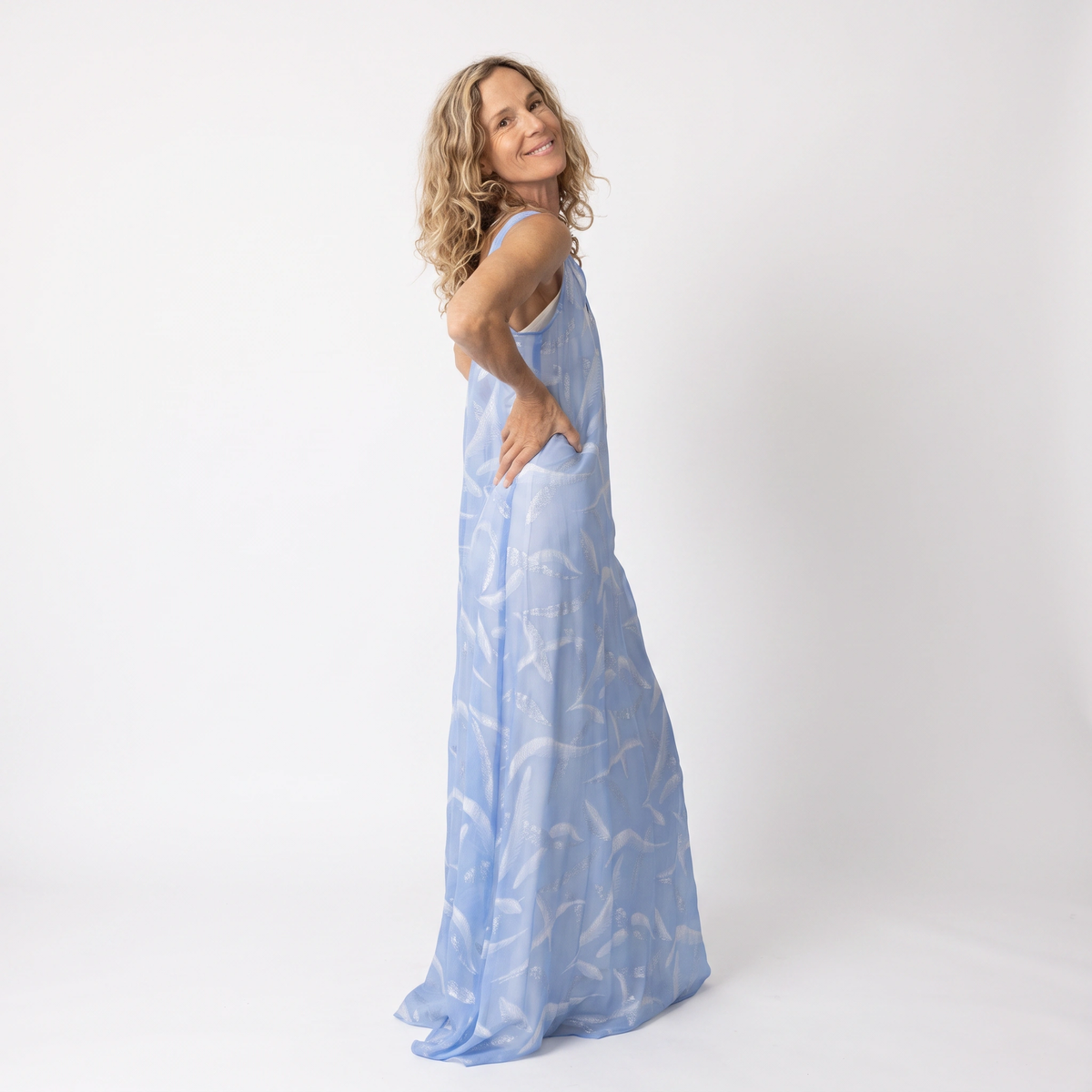 Side view of the Preema Aura Soul Soar sheer blue maxi dress styled over a cream satin slip