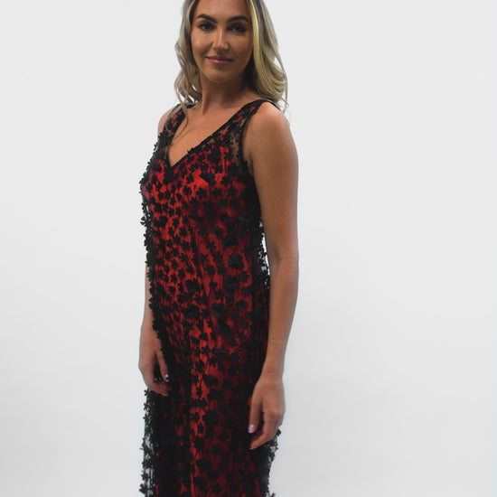 A model showcasing the movement of the Daisy Noir dress, with a red satin slip underneath