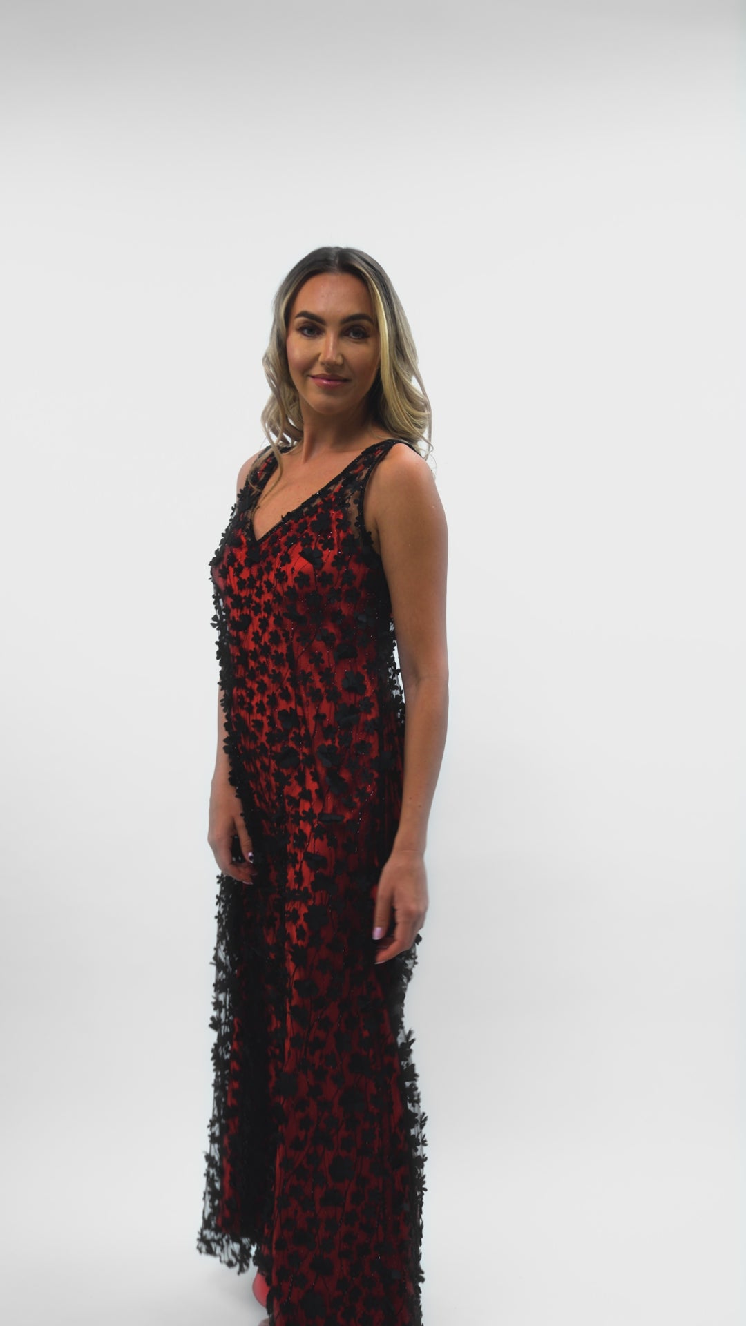 A model showcasing the movement of the Daisy Noir dress, with a red satin slip underneath